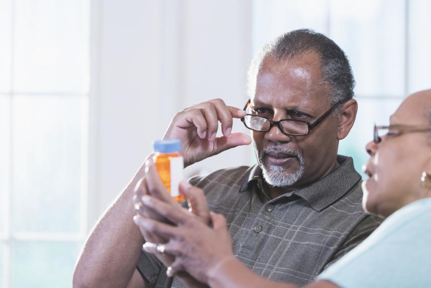 A couple holds up a prescription bottle and reads it together.