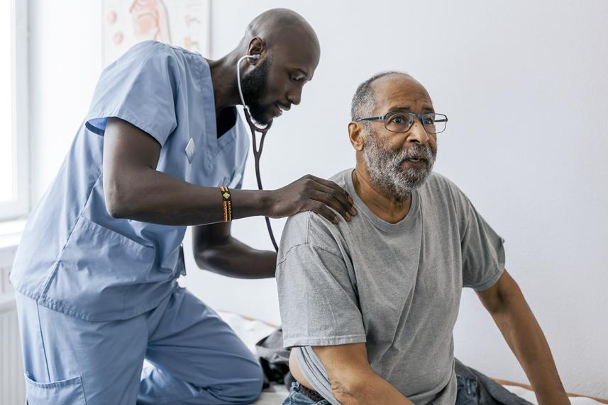 Male doctor using stethoscope to listen to male patient's heart