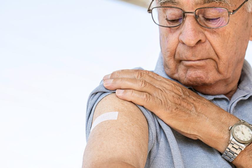 Senior man looking at arm with bandage