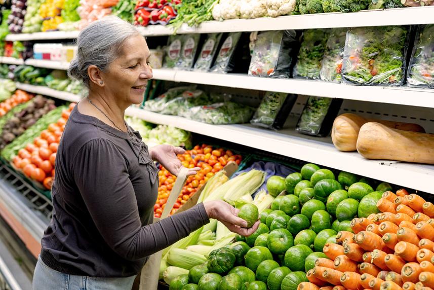 Mature woman shopping for vegetables in produce aisle of supermarket