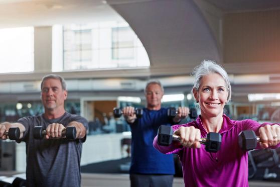 Group of adults working out in class with weights at gym