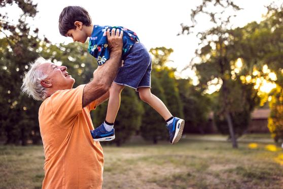 Mature man lifting young grandson in air