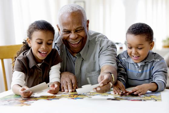 Mature man doing puzzle with grandchildren