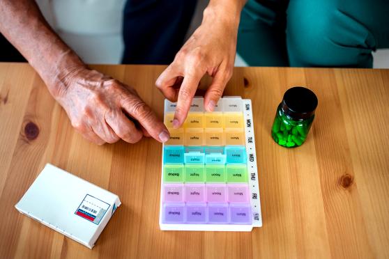 Person's hands using medication organizer