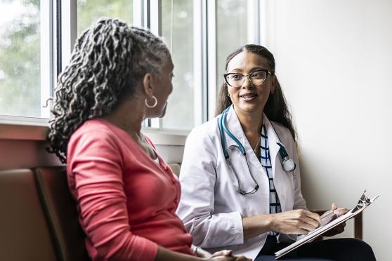 Mature woman talking in person with female health professional