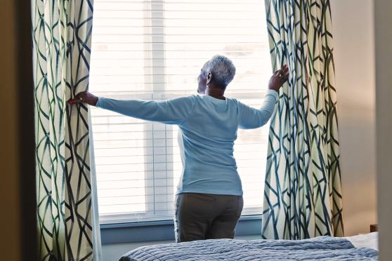 Mature woman opening curtains