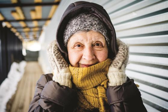 Woman wrapped up in coat, scarf, and mittens.